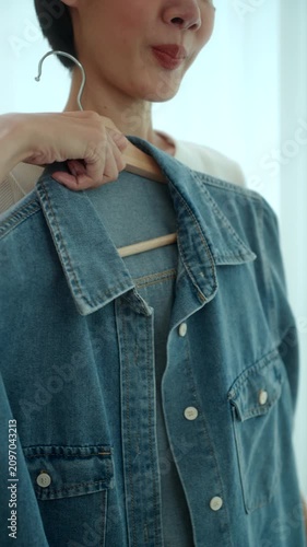 Close-up Woman choosing and trying on clothes in front of a mirror at home. Outfit selection. Capsule wardrobe, personal styling, sustainable fashion. Self-confidence and morning routine concept.
