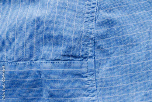 Quadro su tela Close-up of blue woven fabric with thin white stripes, overlapping sections, visible stitching, and natural wrinkles