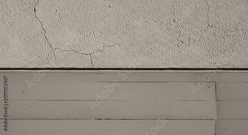 A close-up view of a cracked concrete wall with a wooden panel below