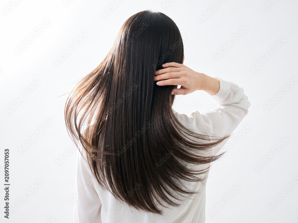 Fototapeta premium 指先で髪に触れながら風になびく美しいストレートヘアの後ろ姿の女性