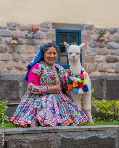 Woman posing with an alpaca in the historic city of Cusco, Peru, surrounded by traditional Andean architecture, showcasing local culture, tourism and the cultural heritage of the Peruvian Andes.
