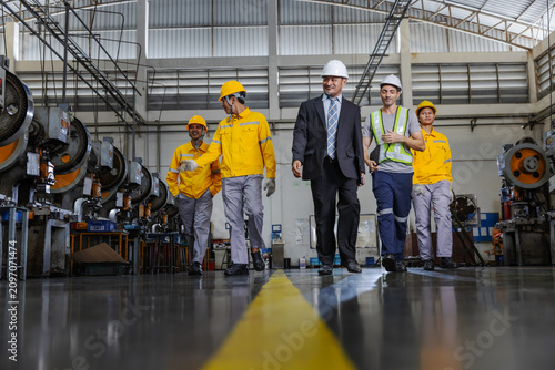 Manufacturing Team Walking Together on Industrial Factory Floor with Engineering Leadership