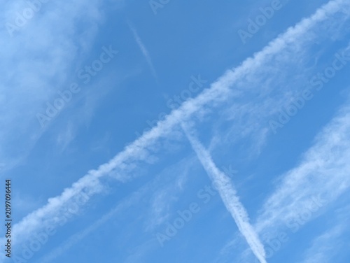 Blue Skies with wispy chemtrail aeroplane lines and fluffy white clouds
