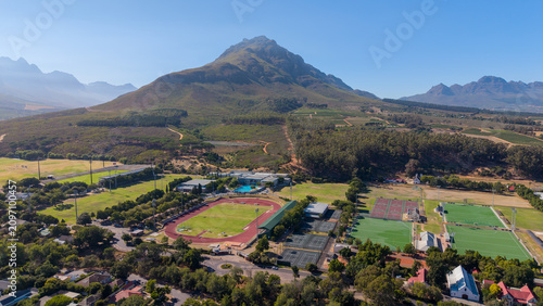 Aerial view of Stellenbosch University sports facilities with the surrounding mountains under a clear blue summer sky. A scenic blend of education, sport and the Cape Winelands landscape.