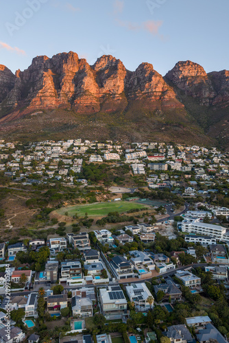 Evening view of Camps Bay, South Africa, as dusk settles over the Atlantic coastline. The Twelve Apostles mountain range glows in the fading light, creating a breathtaking coastal scene.