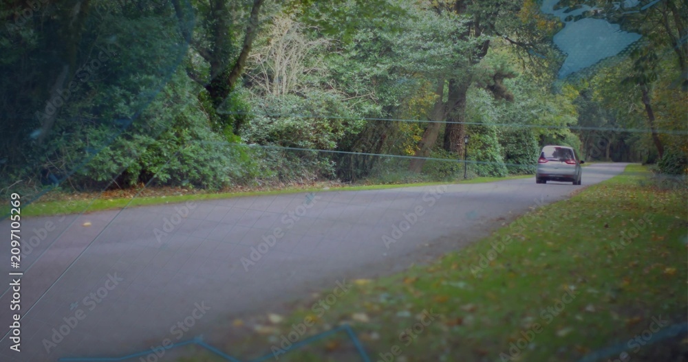 Obraz premium Entering left, silver van moving right along tree-lined road, faint map overlay guiding route