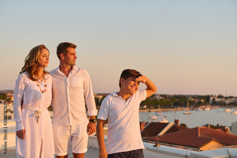 Obraz premium Family on Rooftop Terrace Overlooking Seaside Harbor at Sunset in Umag, Croatia