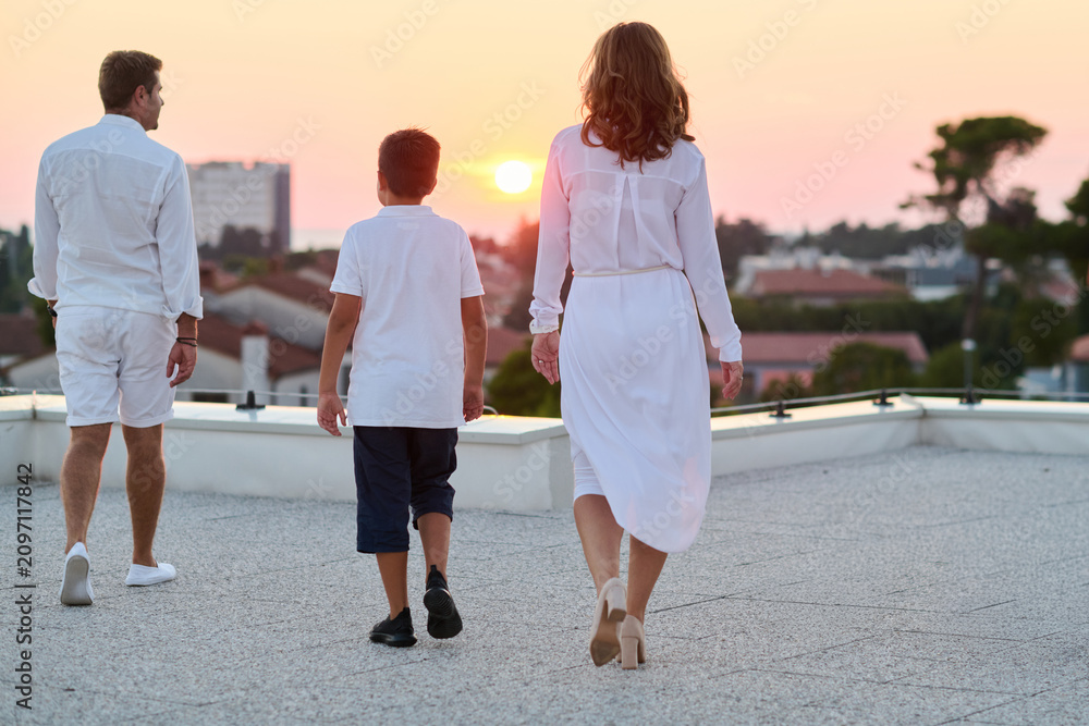 Obraz premium Family Walking on Rooftop Terrace at Sunset With Sea View and Relaxed Evening Mood