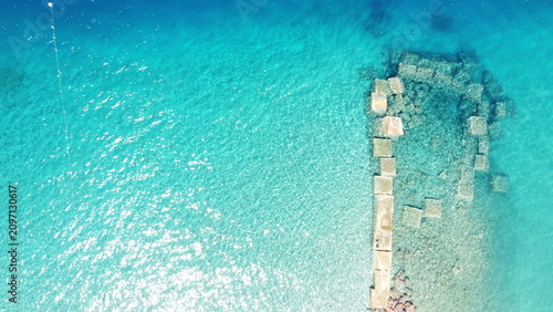 Aerial drone view of submerged stone blocks in crystal clear turquoise sea water