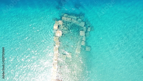 Aerial drone view of submerged stone blocks in crystal clear turquoise sea water