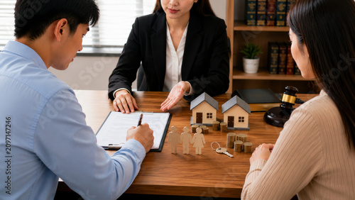Mortgage home finance contract consultant couple house investment meeting at office table, signing document beside model house, coin stack, key, gavel for property loan approval