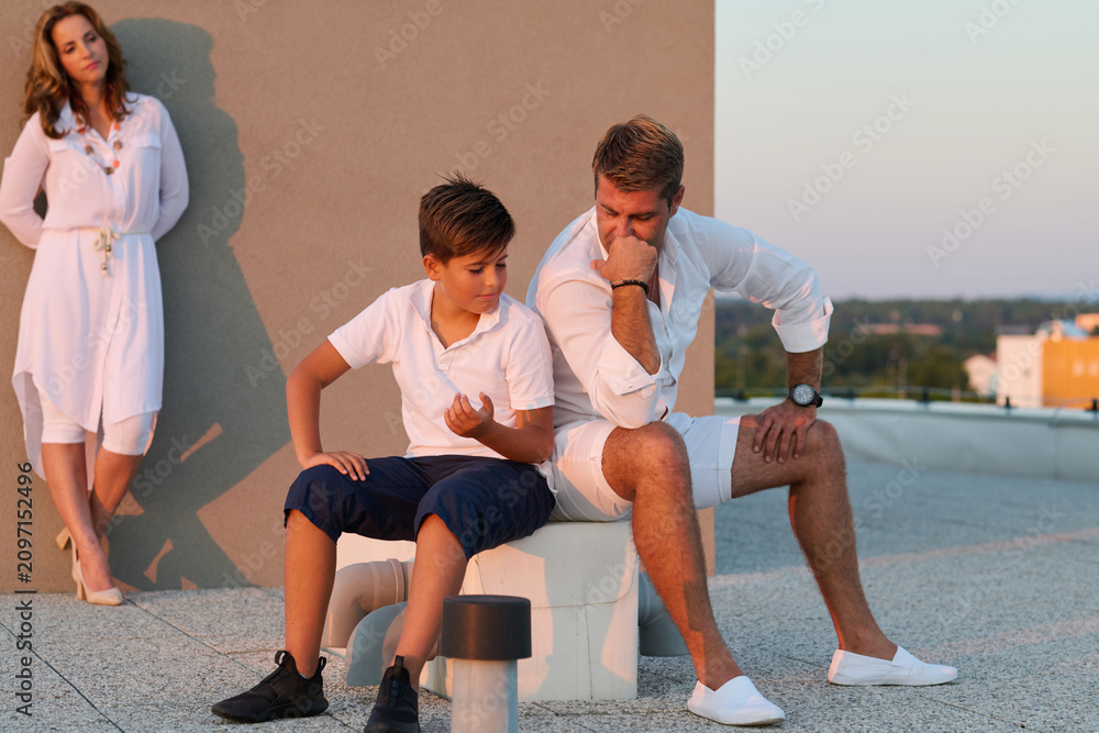 Obraz premium Family Moment on Rooftop Terrace With Father and Son Having a Quiet Conversation at Sunset
