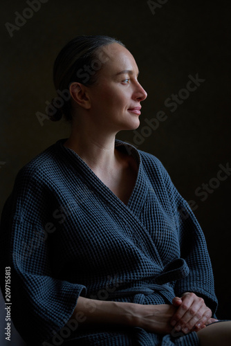 Mature woman in a bathrobe finds serenity at home