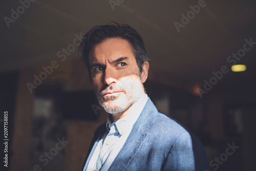 Businessman with hair stubble frowning in hotel
