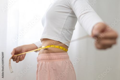 Принти на полотні Young woman measuring slim waist with tape measure