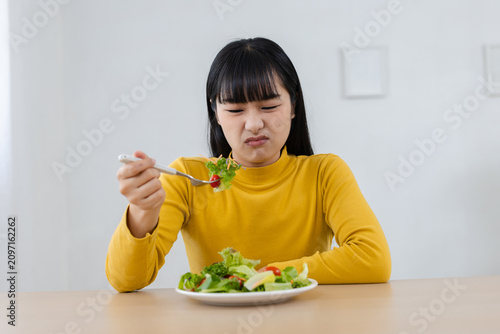 Fotografía Unhappy young Asian woman looking at food with disgusted expression