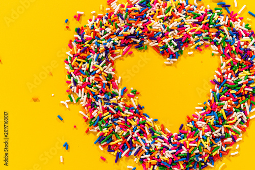 Colorful candy heart shape on yellow surface