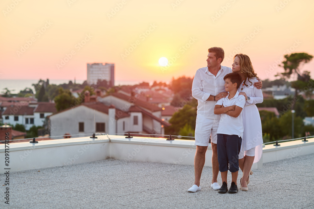 Obraz premium Family on Rooftop Balcony at Sunset With Sea View Over Coastal Town