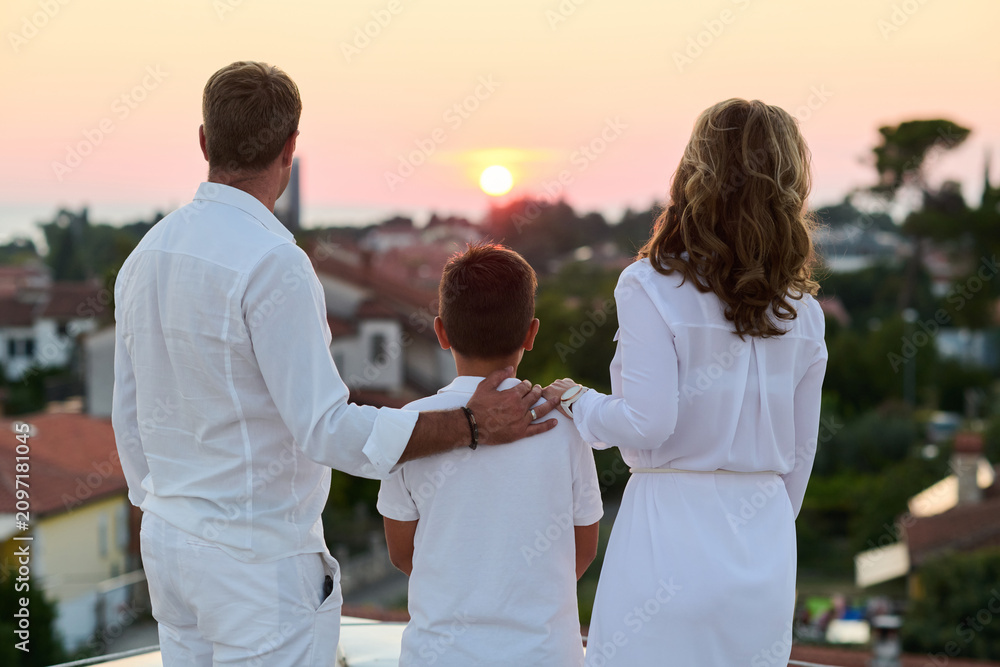 Obraz premium Family Watching Sunset From Rooftop Balcony With Sea View — Parents and Son Together