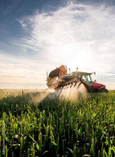 Farmer in tractor spraying crops at sunset
