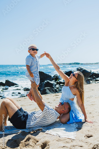 Sticker Family enjoys time at the beach with child on a sunny day while playing near the