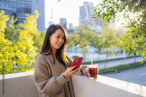Woman looking at smartphone with iced coffee