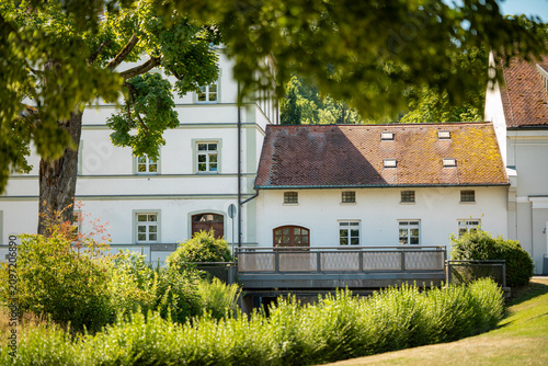 Foto Traditional Bavarian country house with white facade and wooden roof surrounded