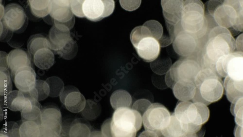 Abstract out of focus silver water bokeh background loop. Shimmering blurry light circles moving on dark backdrop for elegant overlay.