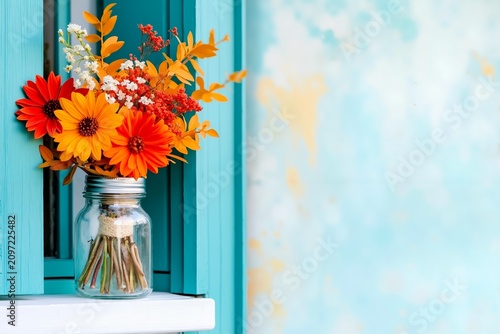 A vase filled with orange and red flowers sitting on a window sill