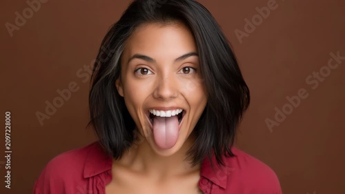 Young woman sticking out tongue in brown studio portrait