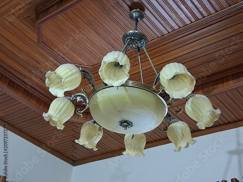 Fotografie Elegant vintage chandelier with multiple decorative glass lamps hanging from a wooden ceiling