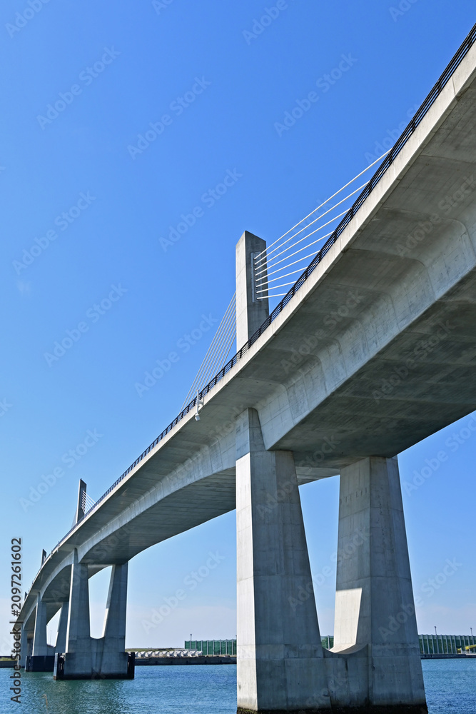 Fototapeta premium Dynamic low angle vertical view of a large concrete cable stayed bridge looking up at pylons under a clear blue sky, Fukushima Japan.