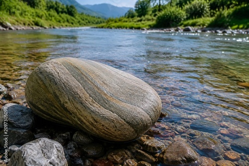 A smooth, curved rock shaped by a flowing stream on a riverbank.