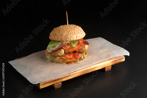 Gourmet chicken burger served on wooden platter with sandwich fastfood parchment vegetables