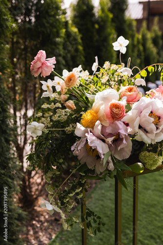 Obraz na płótnie Side view of elegant outdoor wedding floral arrangement on tall stand with peonies and roses