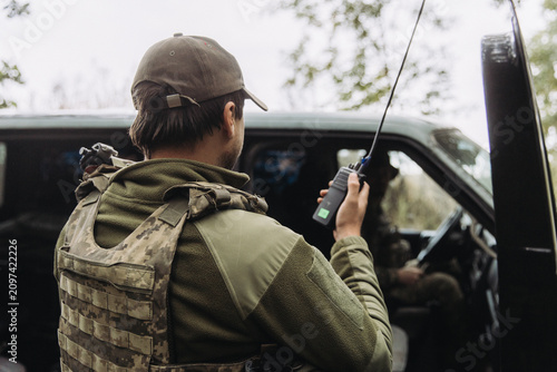 фотографія Ukrainian soldier communicating by radio near military vehicle