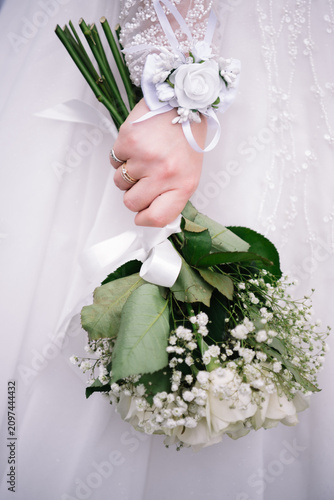 Obraz na plátně Close-up of a bride holding a delicate white wedding bouquet consisting of fresh roses and baby's breath