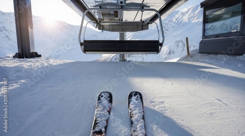 Skier POV on snowy slope with chairlift and mountains