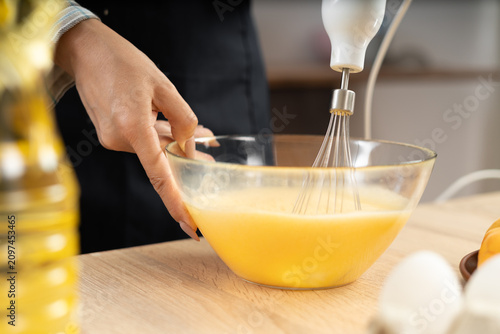 фотографія Close-up of fe,ale chef whisking eggs into bowl, prepare dough for pastries, making homemade dish, new recipe