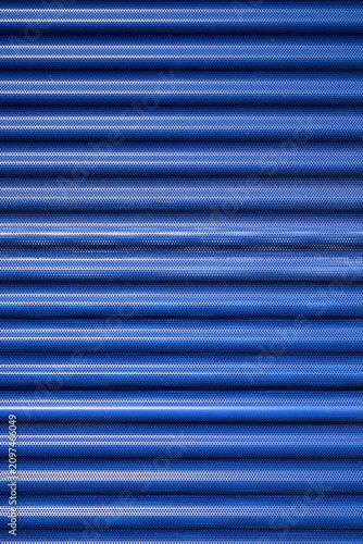 Foto Background created with the foreground of a blue, striated and perforated metallic surface of the facade of a modern building
