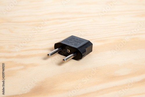 Foto Black plug adapter with metal prongs on wooden surface