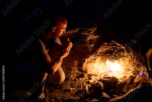 Foto Bald Man Crouches and Watches Eternal Flame at Yanartas Night