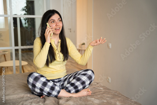 Young woman in casual home setting having a phone conversation with expressive gestures. Remote consultation customer support and emotional communication