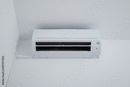 Straight-on shot of a modern white ductless split air conditioner unit with its air flap open.