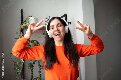 Young woman enjoying music with wireless headphones indoors. Music streaming online entertainment and positive lifestyle