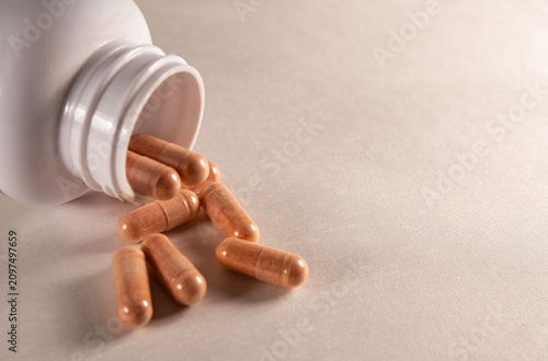 Canvas Print inverted bottle with spilled medicine capsules on a light background
