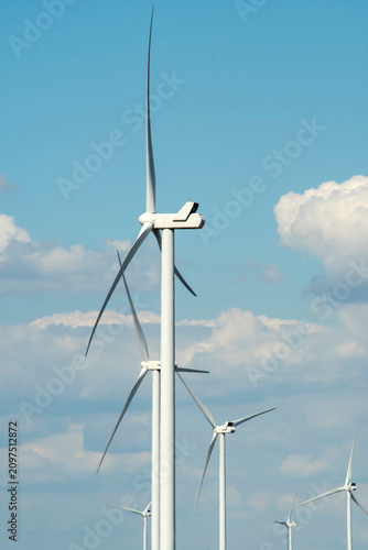 Modern wind power turbine generator against blue sky, alternative sustainable energy concept.

