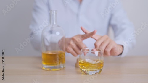 Man making stop hand gesture to refuse a glass of whiskey, Healthy man say no to alcohol drink, stop alcoholism and addiction concept. Responsible man reject a drink before driving and quit booze