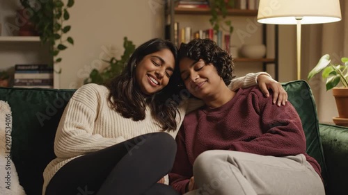 Affectionate young women enjoying cozy evening on sofa