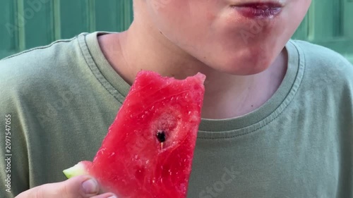 Child eating fresh red watermelon slice outdoors, close-up of kid enjoying summer fruit snack, healthy eating, childhood, summer fun.